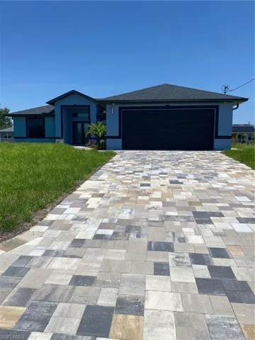 View of front of home with decorative driveway, a garage, a front yard, stucco siding, and a shingled roof