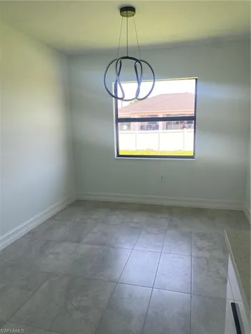 Spare room with baseboards, a chandelier, and tile patterned flooring