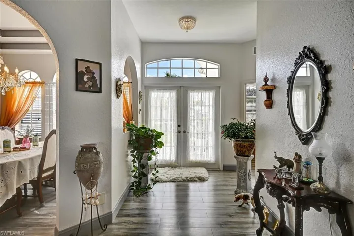 Entryway featuring double French doors, arched walkways, wood style tile floors, and a chandelier