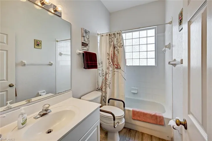 Full bath featuring vanity, shower / bath combo with shower curtain, and light wood style tile floors