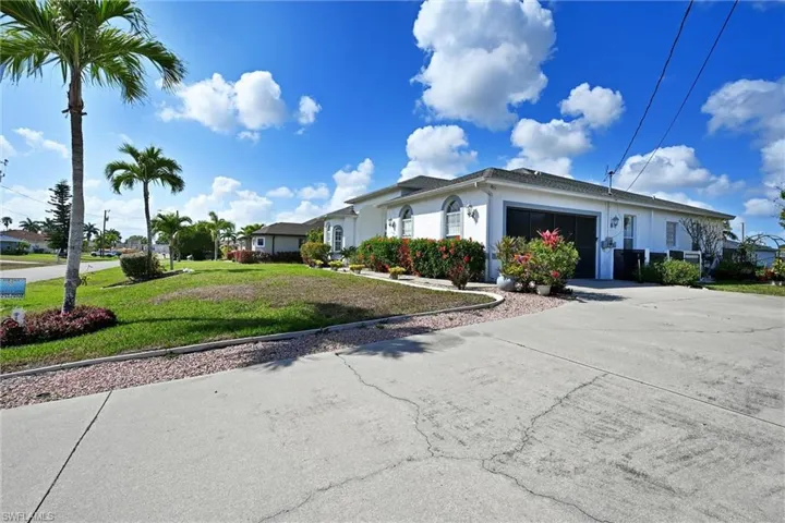 View of front of property with stucco siding, an attached garage, a front yard, and driveway
