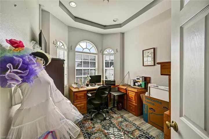 Den/Office area with wood-style tile floors, and a raised ceiling