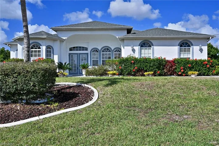 View of front of house with a front yard, stucco siding, and a shingled roof