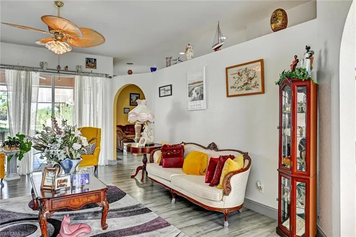 Living room featuring arched walkways, wood style tile floors, and a ceiling fan