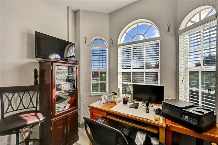 Den/Office area with wood-style tile floors, and a raised ceiling