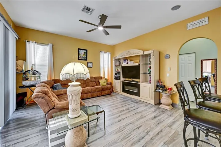 Living area featuring a ceiling fan, wood tile style flooring, and healthy amount of natural light