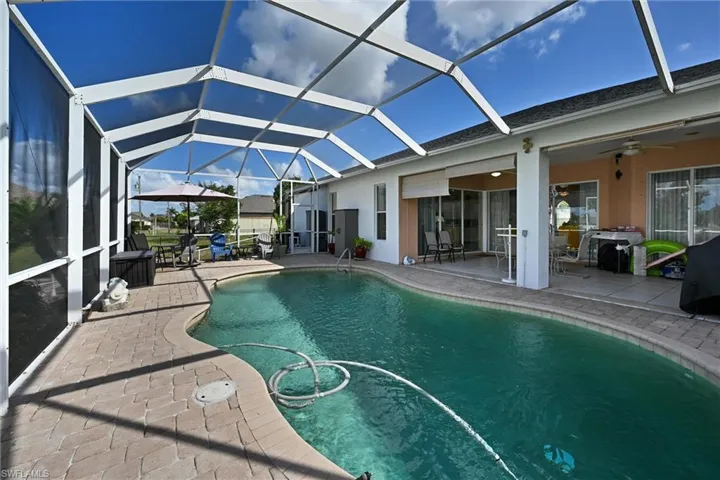 Outdoor pool with a sunroom, a patio area, and a lanai