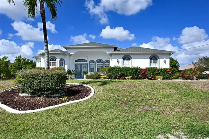 Ranch-style house with stucco finish, landscaped front yard, and a shingled roof