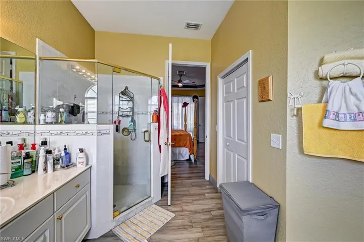 Full bath with 2 vanities, an oversized garden bathtub, and wood style tile floors, jetted tub, and shower stall
