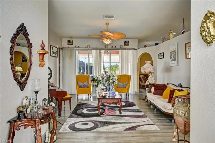 Living room featuring arched walkways, wood style tile floors, and a ceiling fan
