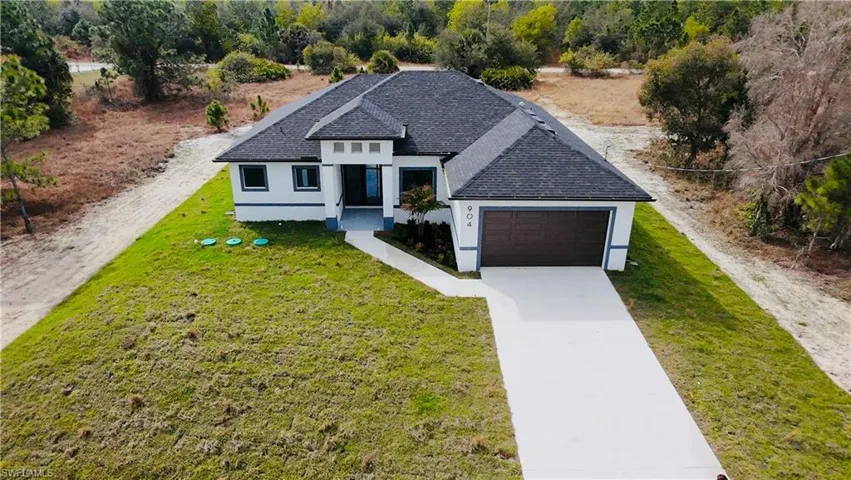 View of front of property with a front lawn, driveway, stucco siding, and an attached garage