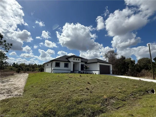 Prairie-style home with an attached garage, a front yard, stucco siding, and driveway