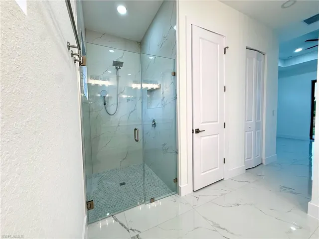 Bathroom with a marble finish shower, a closet, marble look tiles, and recessed lighting