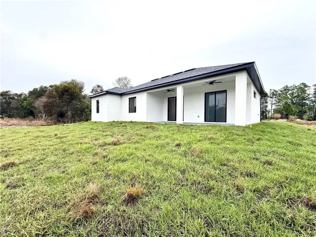 Back of property featuring ceiling fan, stucco siding, a yard, and a patio