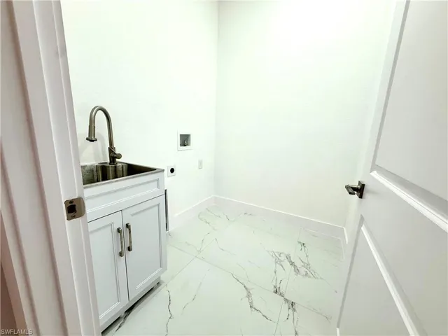 Laundry area featuring light marble finish flooring, cabinet space, washer hookup, and hookup for an electric dryer
