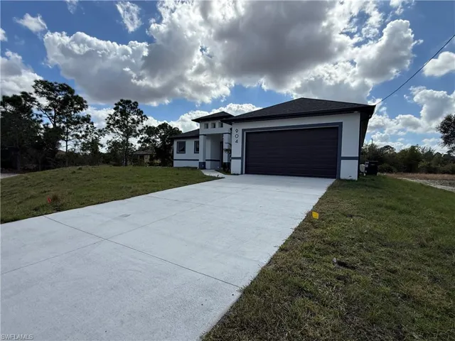 Prairie-style home with a front lawn, concrete driveway, an attached garage, and stucco siding