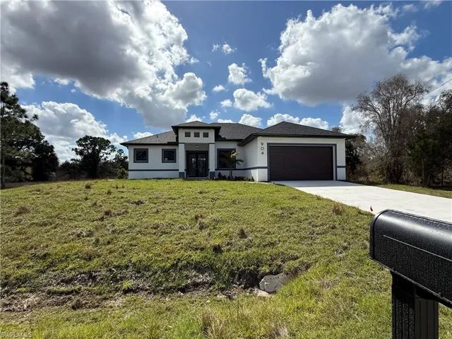 Prairie-style house featuring an attached garage, stucco siding, concrete driveway, and a front yard