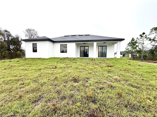 Back of property with stucco siding, a lawn, a patio area, and ceiling fan