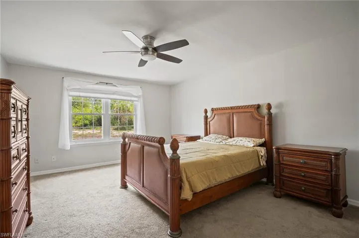 Bedroom featuring light carpet, baseboards, and a ceiling fan
