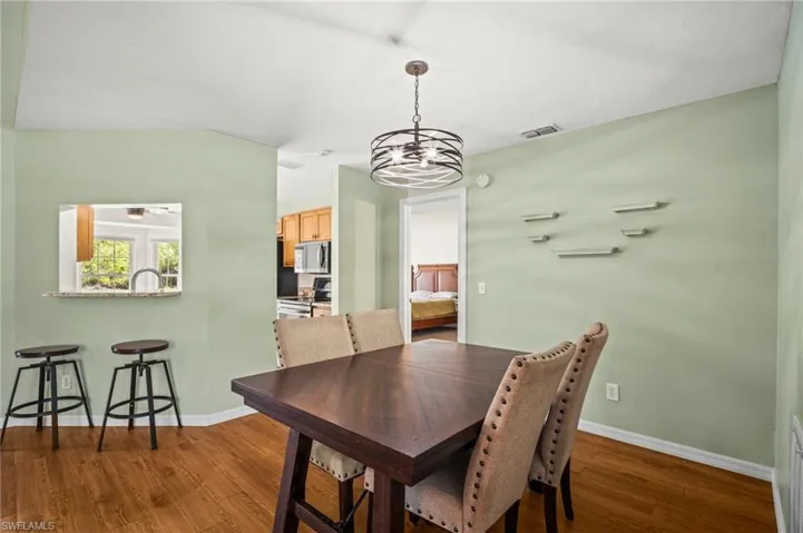 Dining area with wood finished floors, a chandelier, and baseboards