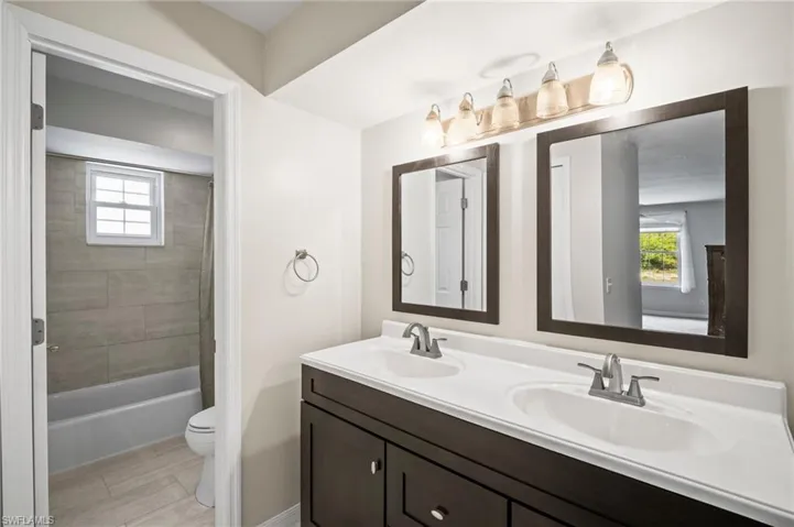 Full bath featuring double vanity, toilet, and shower / bath combination