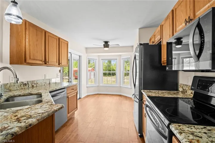 Kitchen featuring appliances with stainless steel finishes, a sink, light wood-style flooring, brown cabinets, and healthy amount of natural light