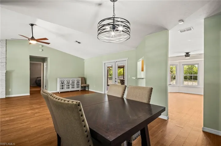 Dining area with ceiling fan, lofted ceiling, french doors, wood finished floors, and a chandelier