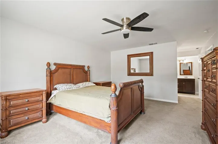 Bedroom featuring light colored carpet, baseboards, ensuite bathroom, ceiling fan, and a sink