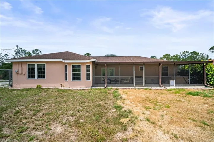 Rear view of house featuring a sunroom and stucco siding