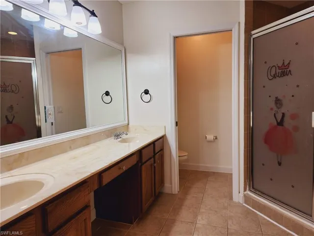 Master Bathroom featuring dual sinks, toilet, tile floors, a shower with separate bathtub, and large vanity