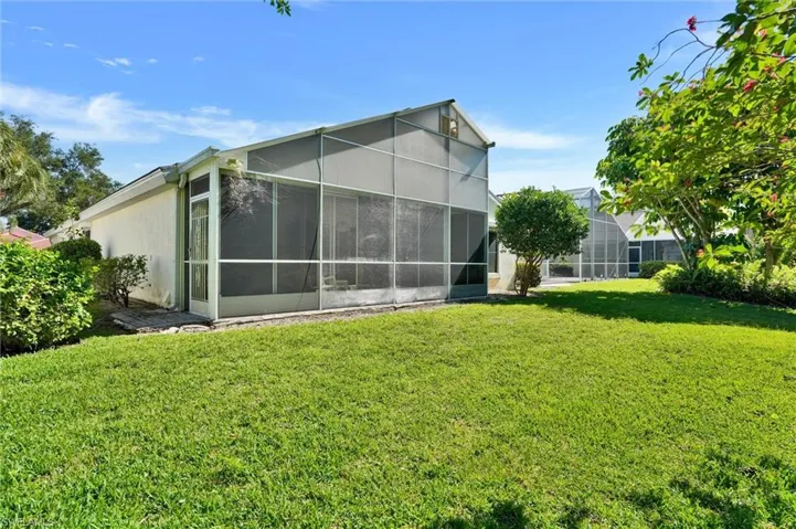Expansive green lawn bordering a screened enclosure with a peaked roofline