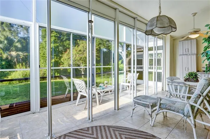 Screened-in porch featuring tiled flooring, a ceiling fan, and built-in white cabinetry