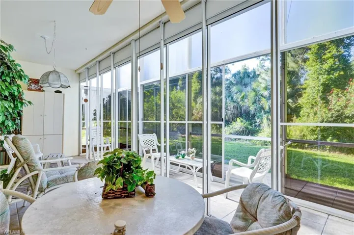 Screened lanai featuring white framing, multiple ceiling fans, a built-in storage unit, and a tiled floor