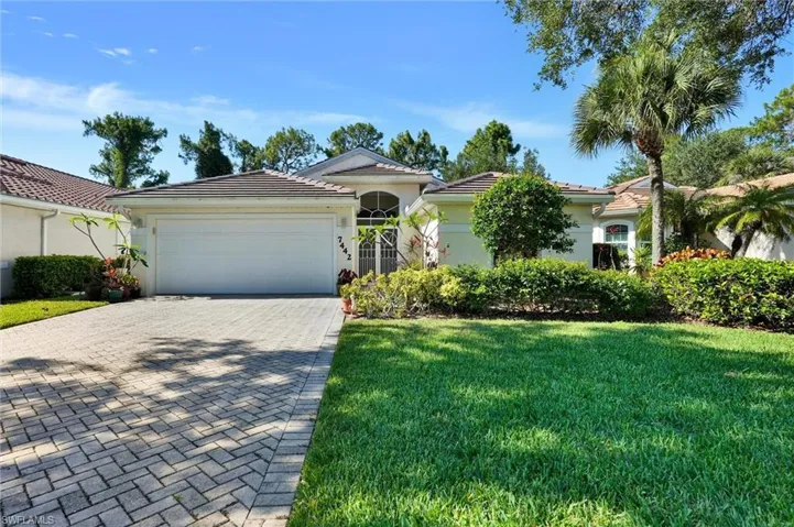 Single-story residence featuring a tile roof, a two-car garage, and a paver driveway