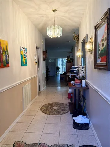 Corridor with light tile  flooring, a chandelier, and a textured wall