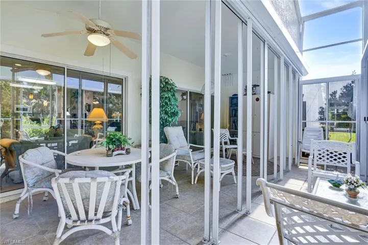 Screened lanai featuring a ceiling fan with integrated lighting, tiled flooring, and a glass-paneled entry door