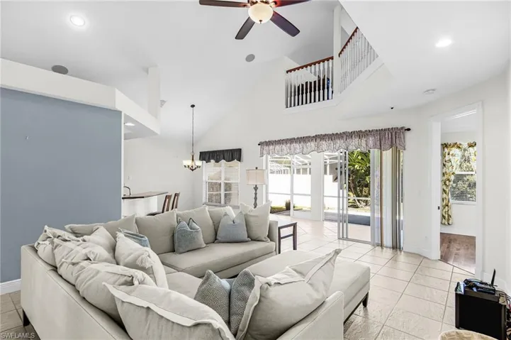 Living area featuring a chandelier, ceiling fan, and lofted ceiling