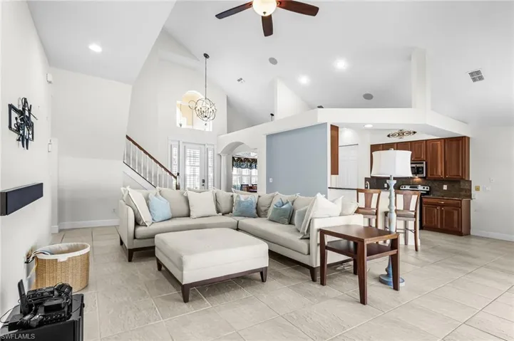 Living area featuring hanging lights, ceiling fan, lofted ceiling, and arched walkways