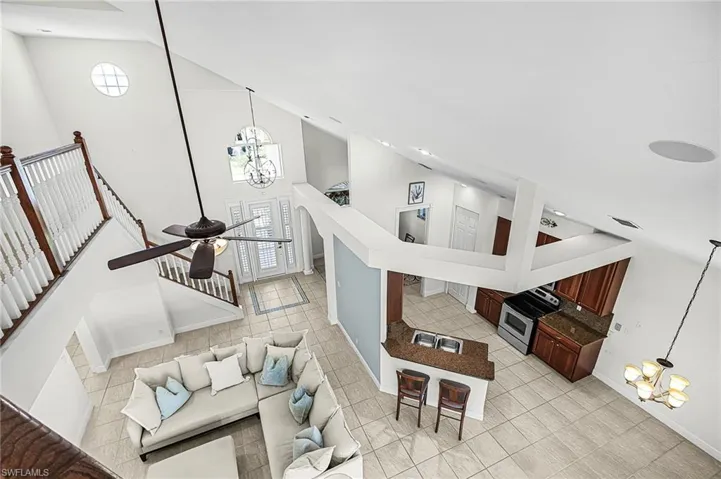 Living area featuring hanging lights, vaulted ceiling, and light tile patterned floors