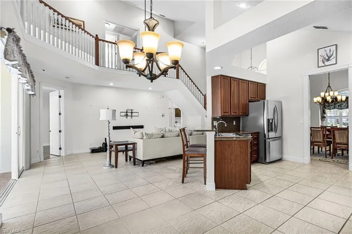 Kitchen with hanging lights, a kitchen bar, open floor plan, stainless steel fridge, and a peninsula