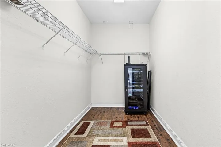 Walk in closet with wine cooler and dark wood-type flooring