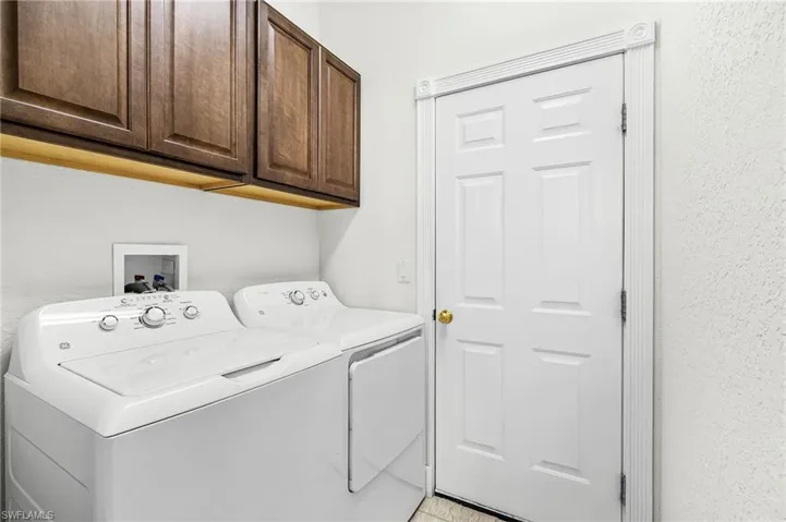 Laundry room with cabinet space, washer and clothes dryer, and a textured wall