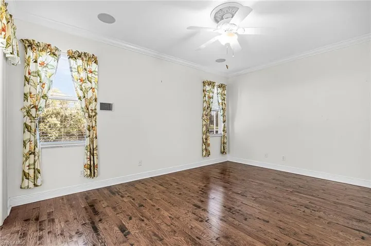 Spare room with ornamental molding, dark wood-style floors, and ceiling fan
