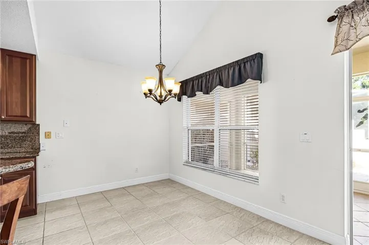 Unfurnished dining area with vaulted ceiling, hanging lights, and healthy amount of natural light