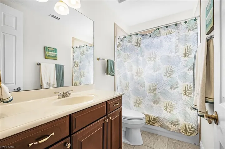 Bathroom with vanity, shower / bathtub combination with curtain, and light tile patterned floors