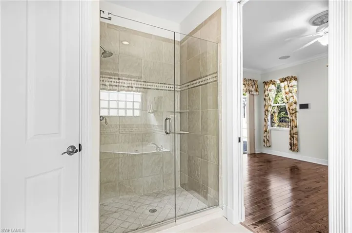 Bathroom with ornamental molding, a shower stall, ceiling fan, and hardwood / wood-style floors