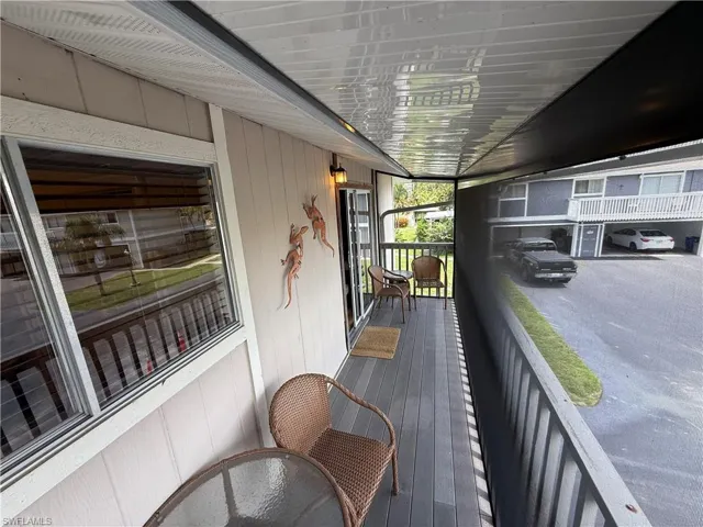 Screened balcony featuring wood-finish decking, white railings, and a sliding glass door entry