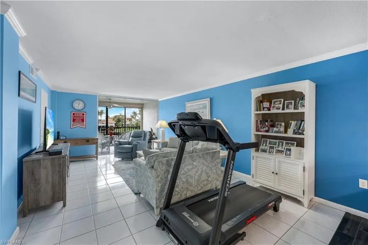 Exercise room with ornamental molding, tile patterned flooring, and ceiling fan