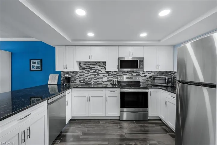 Kitchen with appliances with stainless steel finishes, white cabinets, backsplash, and recessed lighting