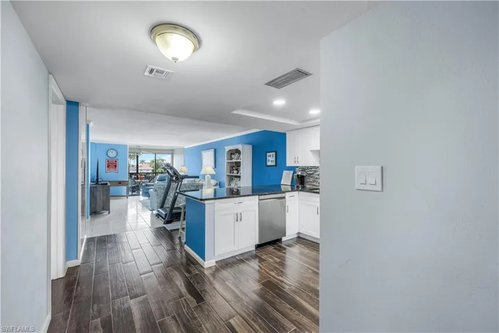 Kitchen with dishwasher, open floor plan, a peninsula, dark countertops, and white cabinets
